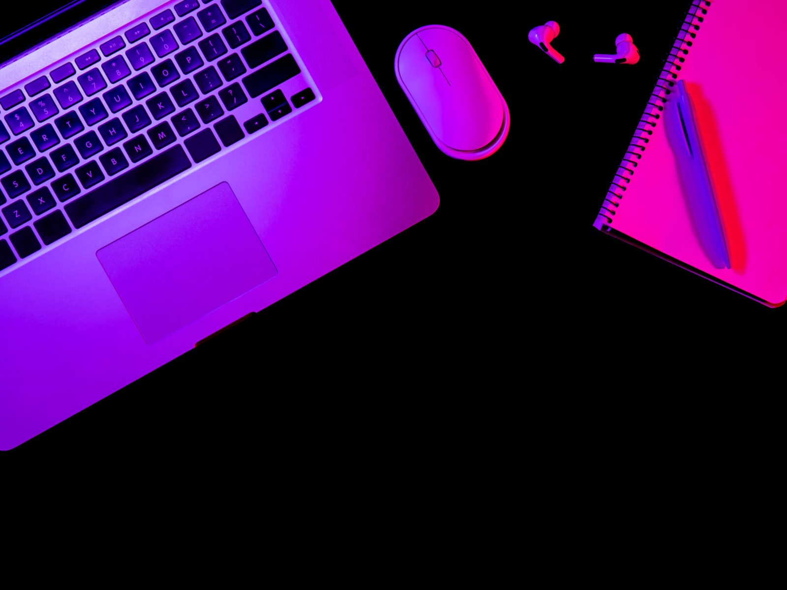 Laptop and notepad on black background with neon light, flat lay, night work concept, copy space.